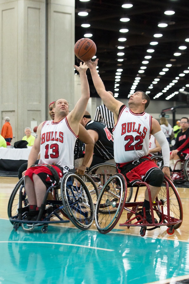 Amputee Wheelchair Basketball player reaching for a ball.